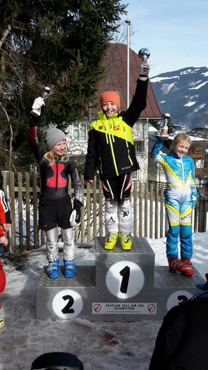 Drei Kinder mit Pokalen auf dem Siegerpodium beim Kindercup in Zell am See.