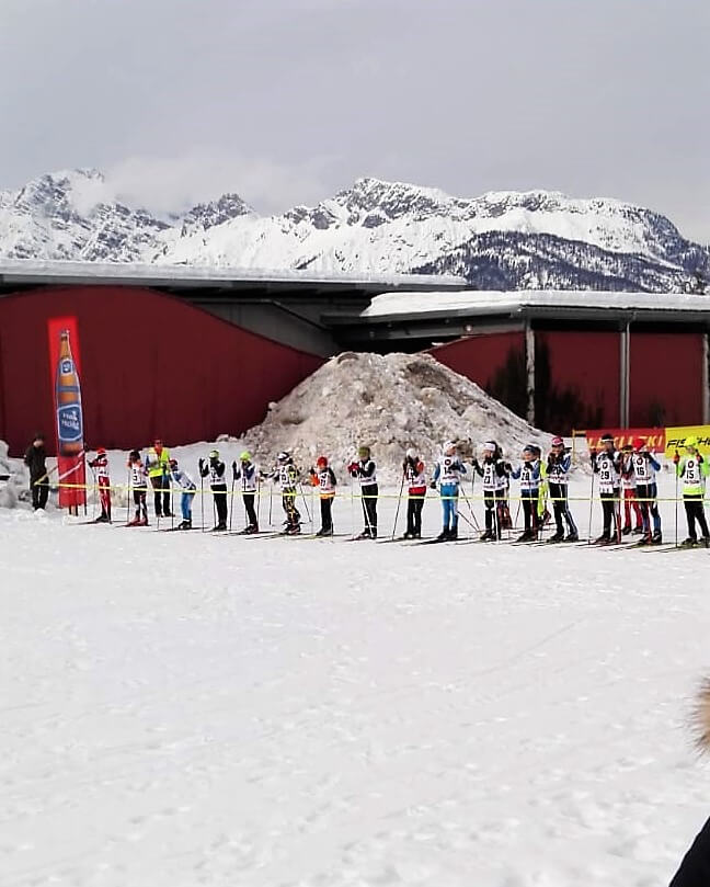 Teilnehmer des Saalfeldener Skimarathons stehen bereit im Schnee bei beeindruckender Bergkulisse.
